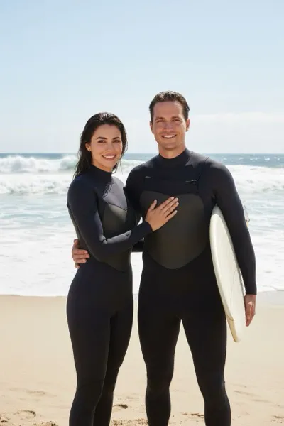 Felszabadult és nyárias hangulatú, AI generált portré egy szörfösről nedves neoprén ruhában, hóna alatt egy szörfdeszkával a homokos tengerparton. A háttérben a habzó óceánhullámok, a távoli horizont és a ragyogó napsütés látható.